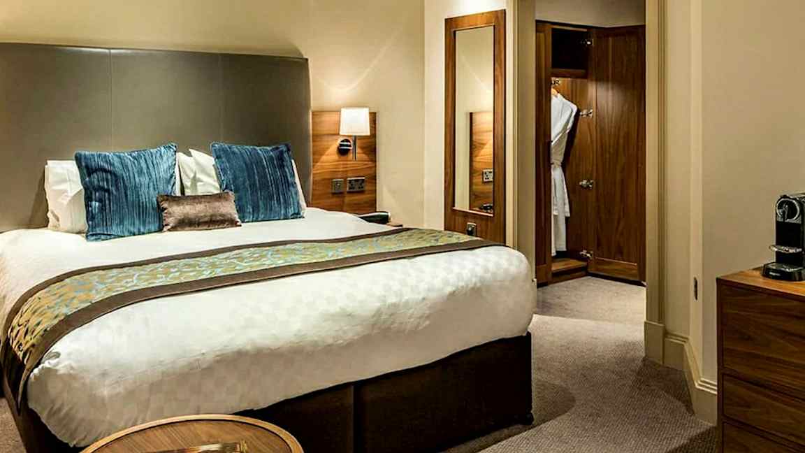 Bild av ett hotellrum med en dubbelsäng, sängbord och garderob i trä. (AI-genererad text)