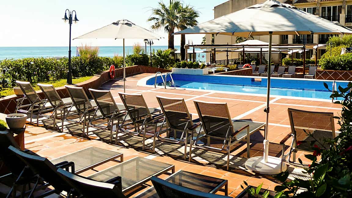 En utomhuspool med solstolar och parasoller. (AI-genererad text)