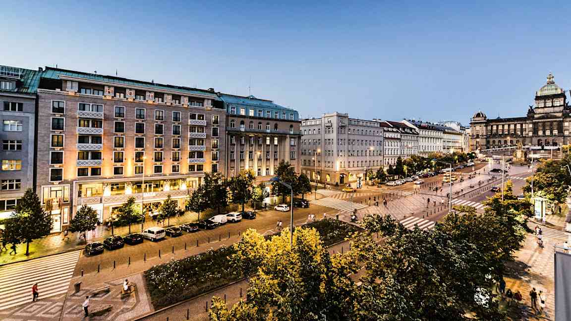 En stadsvy med byggnader, ett torg, belysning och träd. (AI-genererad text)