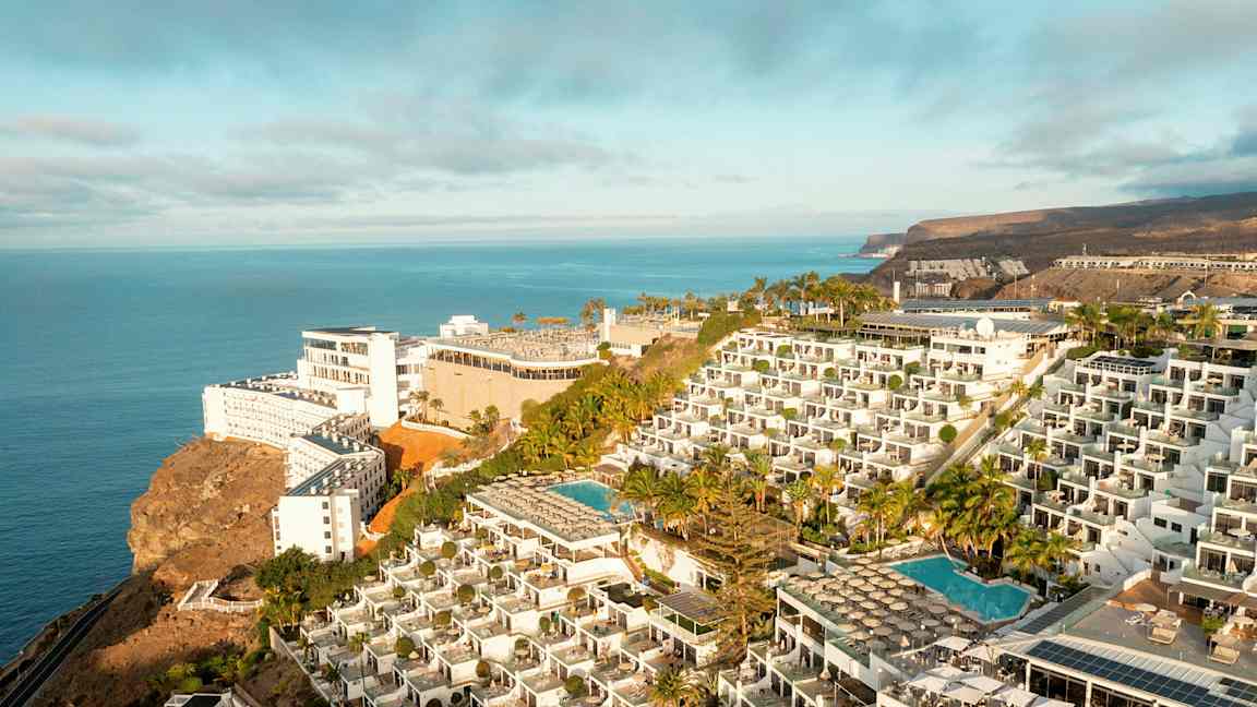 Hotellkomplex på en klippa med pooler och havsutsikt. (AI-genererad text)