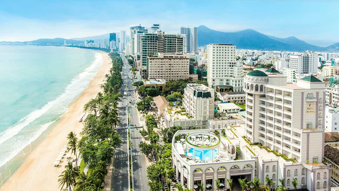 Bild av en stad vid havet med moderna byggnader och en strand med parasoller. (AI-genererad text)