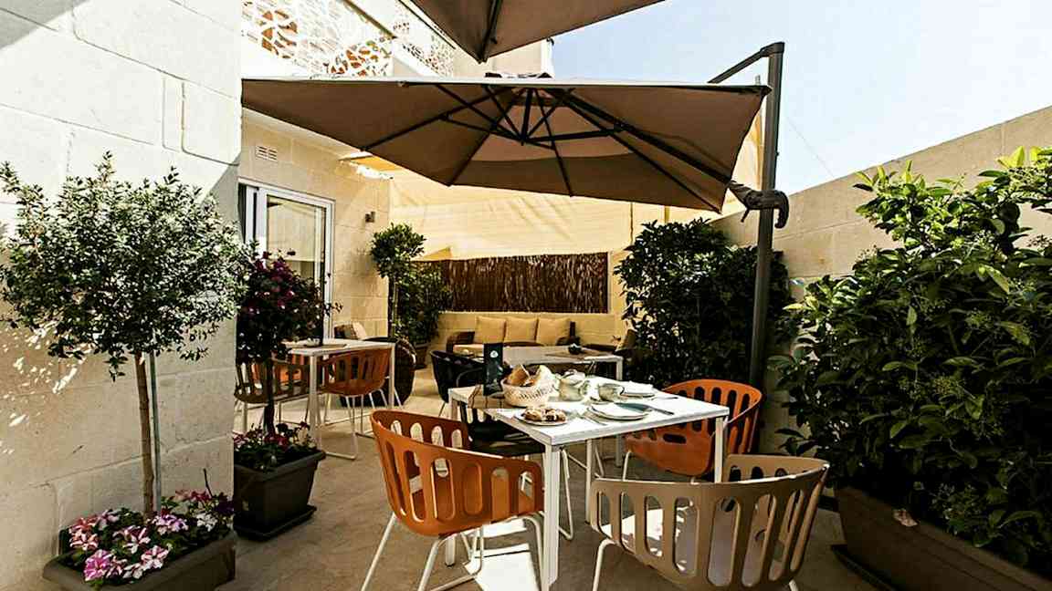 En terrass med utemöbler, parasoll och växter. (AI-genererad text)