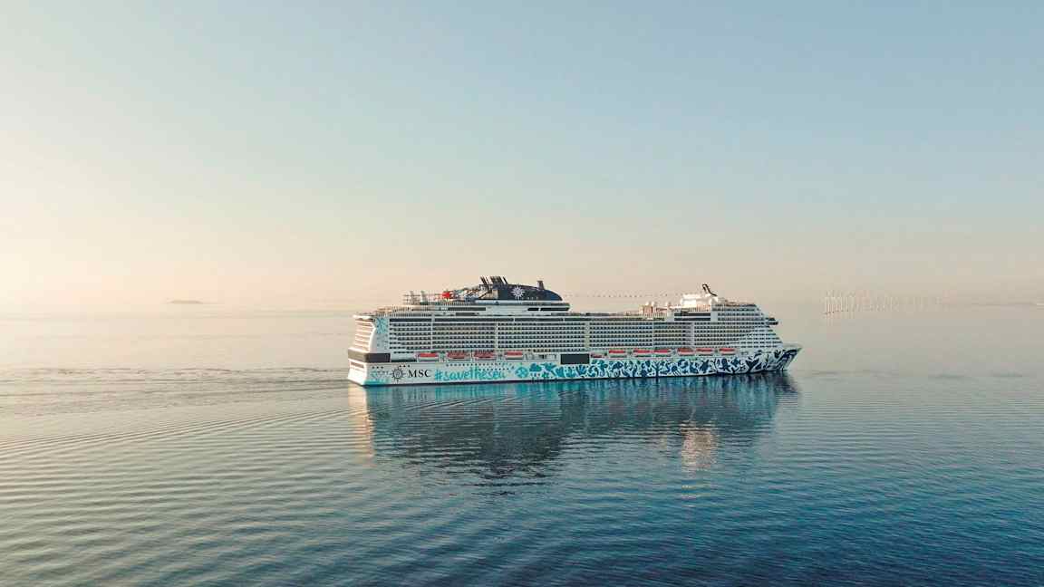 Ett kryssningsfartyg på öppet hav med vindkraftverk i fjärran. (AI-genererad text)