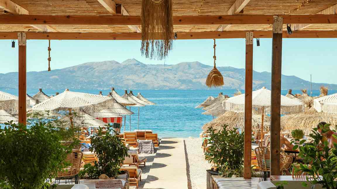 Strandutsikt med parasoller, solstolar och havet i bakgrunden. (AI-genererad text)