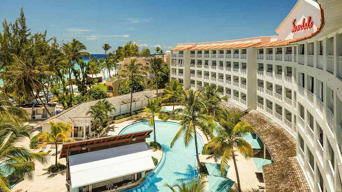 Ett hotell med pool, omgivande palmer och närliggande strand. (AI-genererad text)