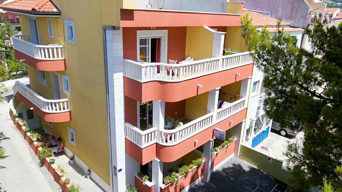 En byggnad med gul och röd fasad, balkonger och en liten innergård. (AI-genererad text)