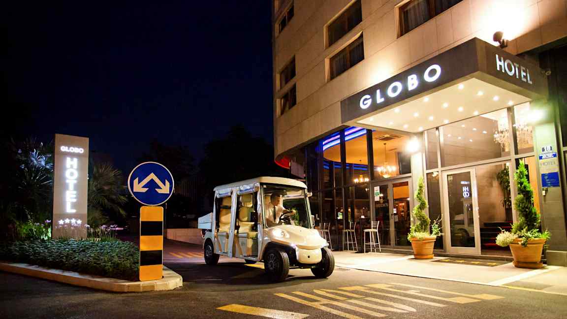 Ett hotell sett på natten med namnet Globo, en elbil står parkerad framför ingången. (AI-genererad text)