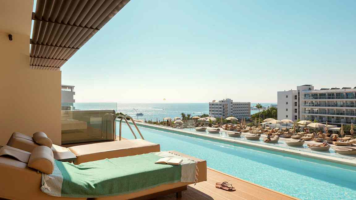 Solstolar och pool med utsikt över havet i en semesterort. (AI-genererad text)