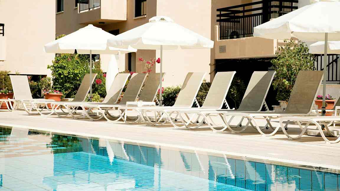 Solstolar vid en pool med parasoller. (AI-genererad text)