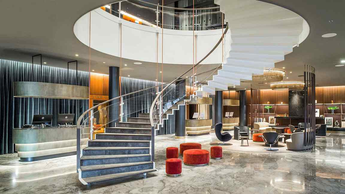 Modernt hotellfoajé med en spiraltrappa och sittplatser. (AI-genererad text)