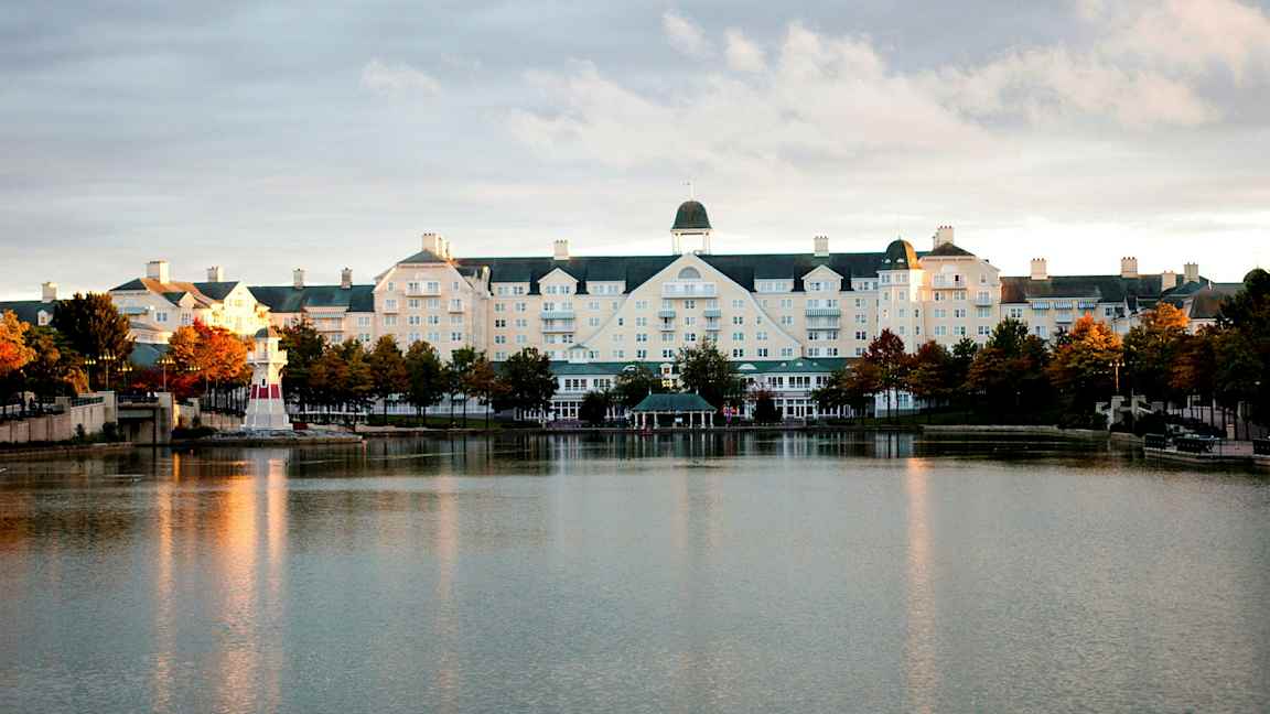 Hotellbyggnad vid en sjö med en liten fyr. (AI-genererad text)