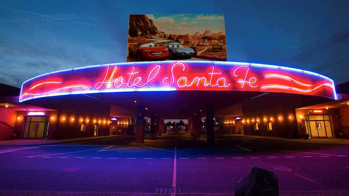 Neonskylten över entrén till Hotell Santa Fe med Disney/Pixar-bilar på affischen ovanför. (AI-genererad text)