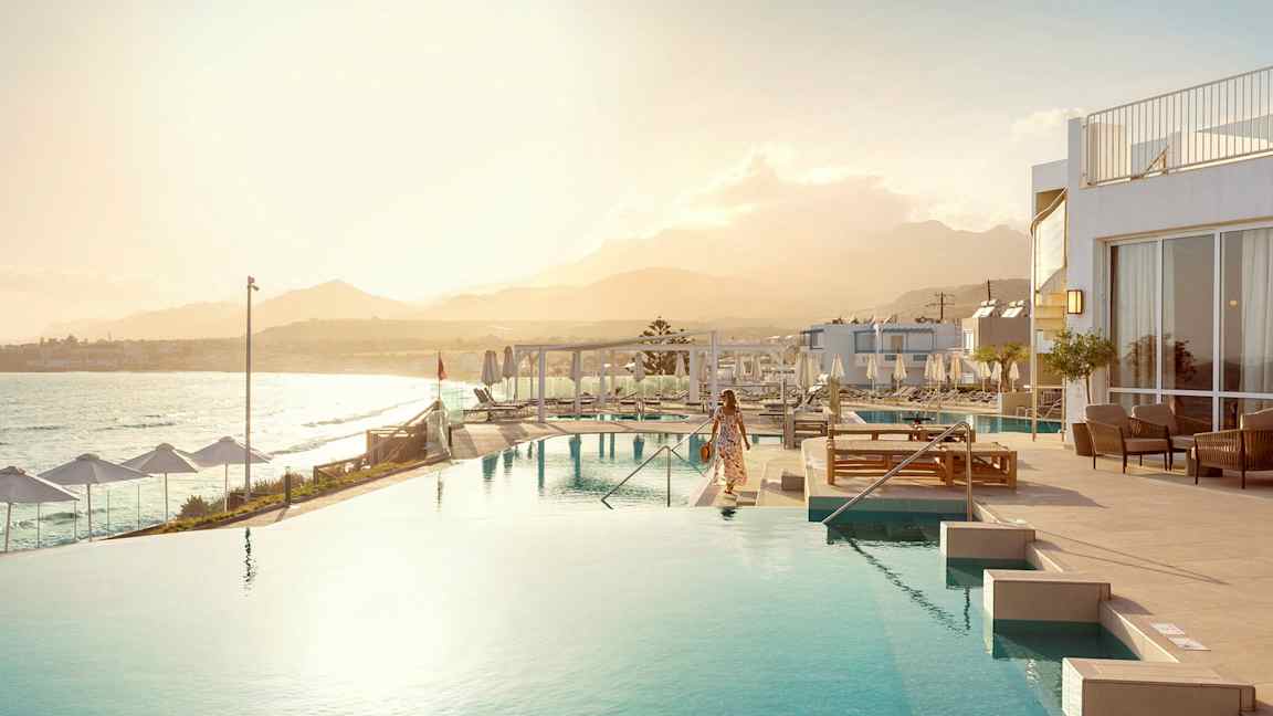 En kvinna vid en infinitypool med havet och en bergskedja i bakgrunden. (AI-genererad text)