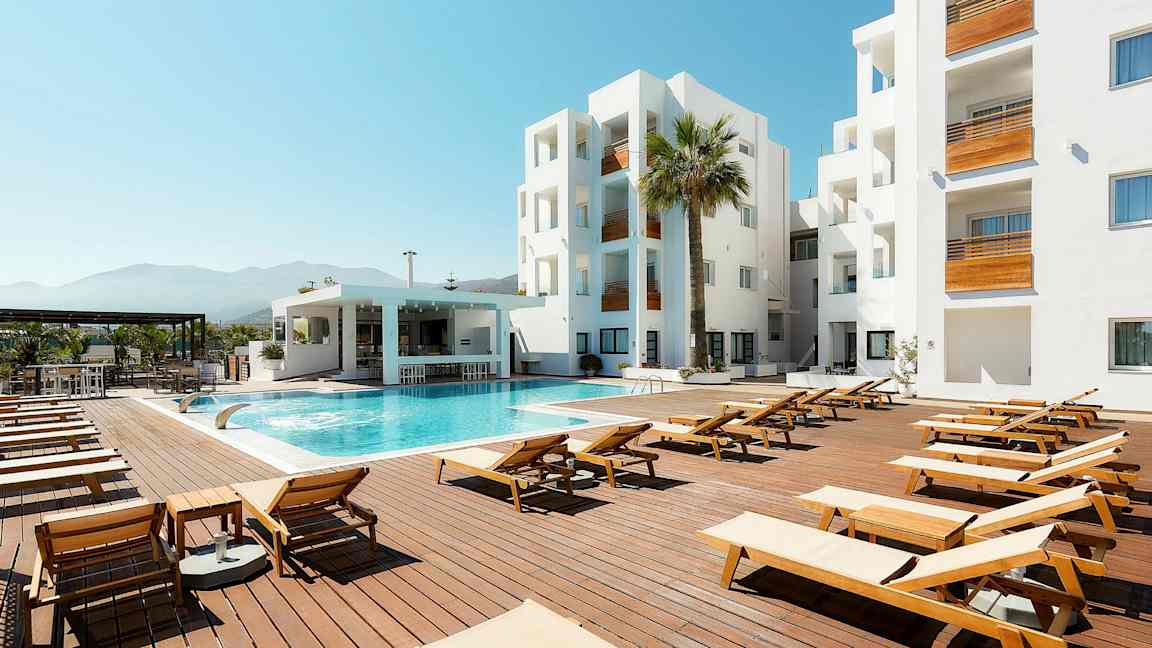 Utomhuspoolområde med solstolar, modern byggnad och blå himmel. (AI-genererad text)