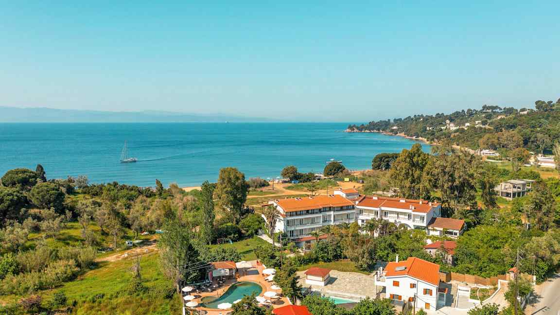 Landskapsbild som visar byggnader med röda tak nära en kustlinje med havsutsikt. (AI-genererad text)