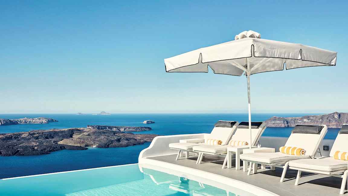 Soldäck vid en infinitypool med utsikt över havet och klippor i bakgrunden. (AI-genererad text)