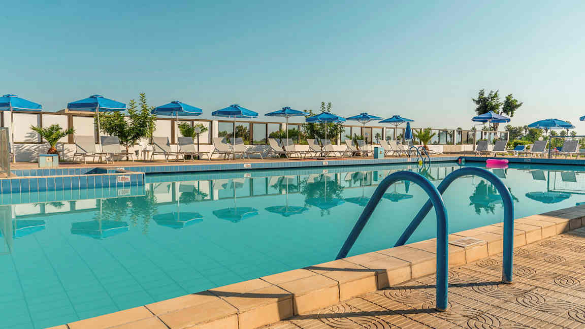 Bild av en utomhuspool med blå parasoller och solstolar runtom. (AI-genererad text)
