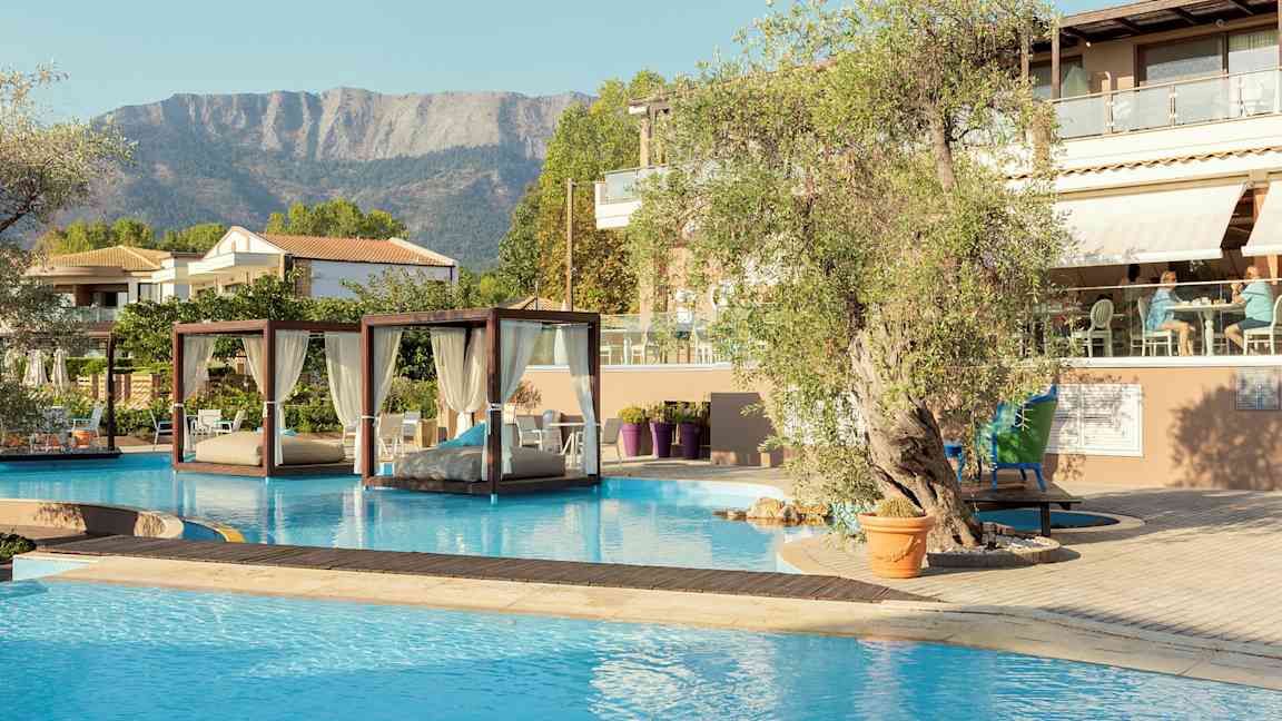 En pool med balinesiska dagbäddar och ett hotell med sittområde i bakgrunden. (AI-genererad text)