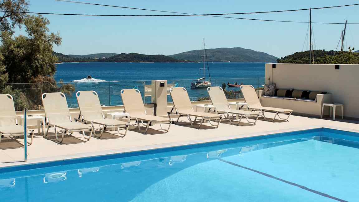 Swimmingpool med solstolar och havsutsikt i bakgrunden. (AI-genererad text)