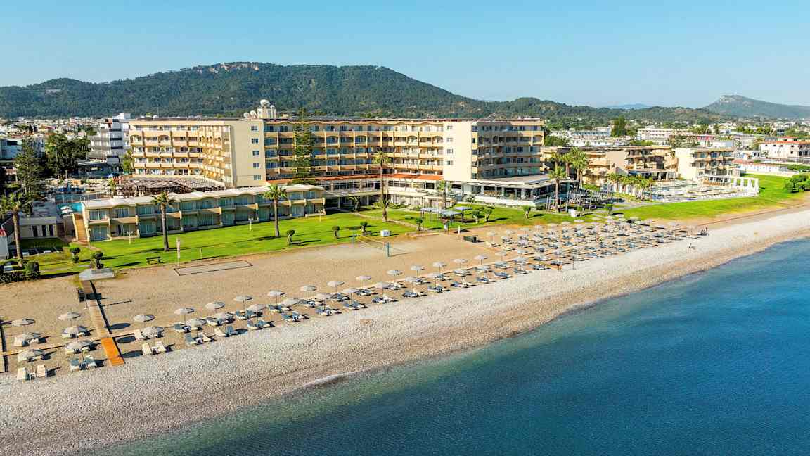 Hotellet vid stranden med solstolar och parasoller på sanden. (AI-genererad text)