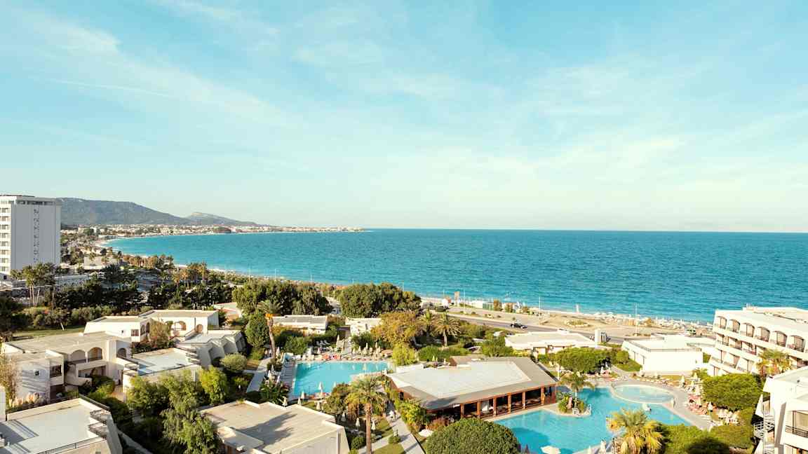 Vy över hotellområde med pooler och havet i bakgrunden. (AI-genererad text)