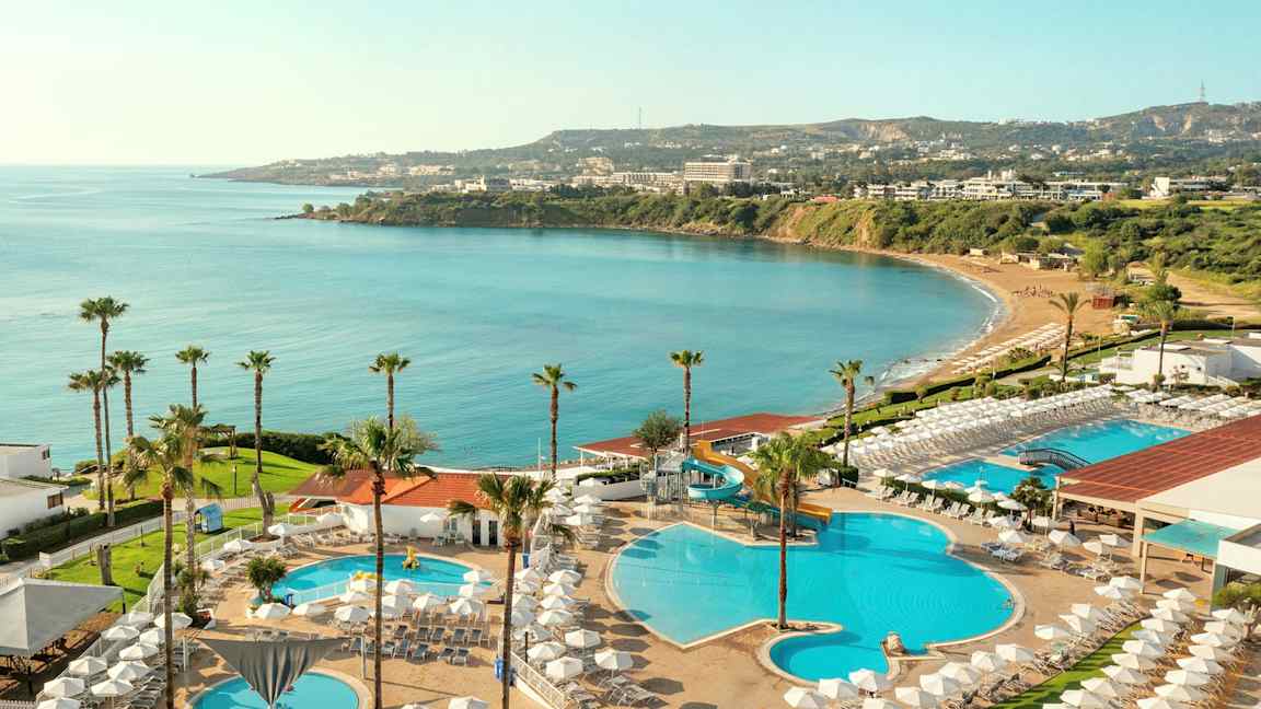 Utsikt över hotellområde med pooler, solstolar och havsutsikt. (AI-genererad text)