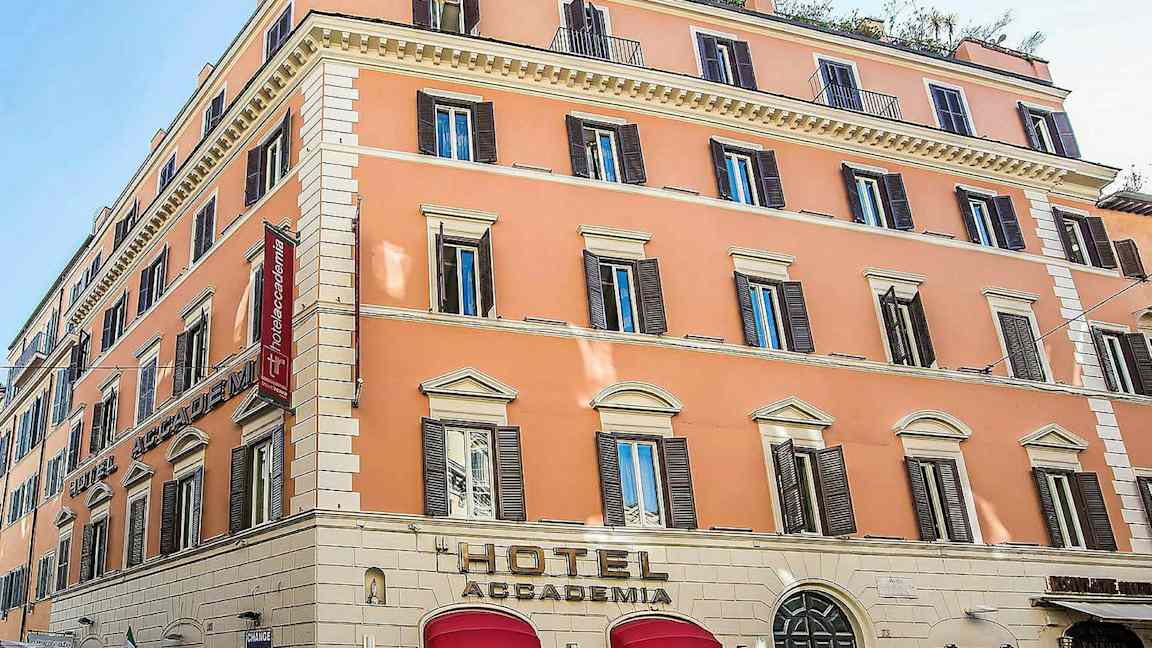 Ett hotell i en pastellfärgad byggnad med flera våningar och många fönster. (AI-genererad text)