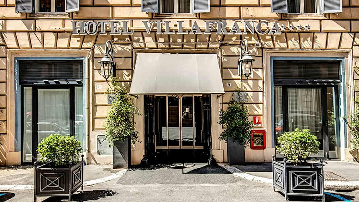 Hotellentré med skylt, fönster och växter i krukor. (AI-genererad text)