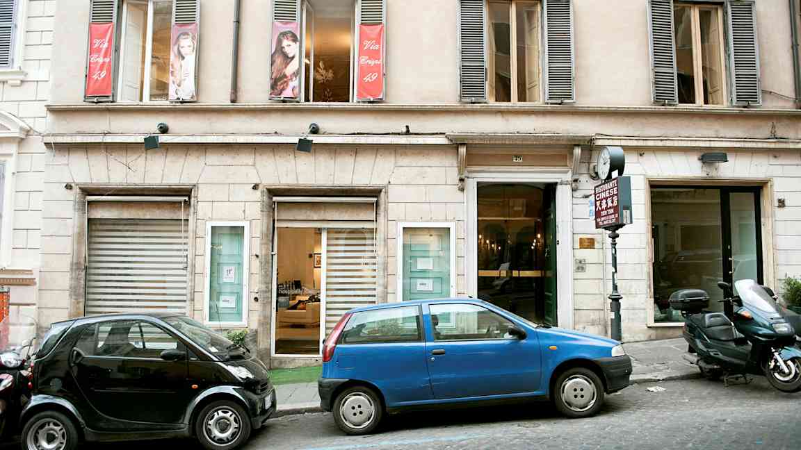 Fasad av byggnad med parkerade bilar framför. (AI-genererad text)