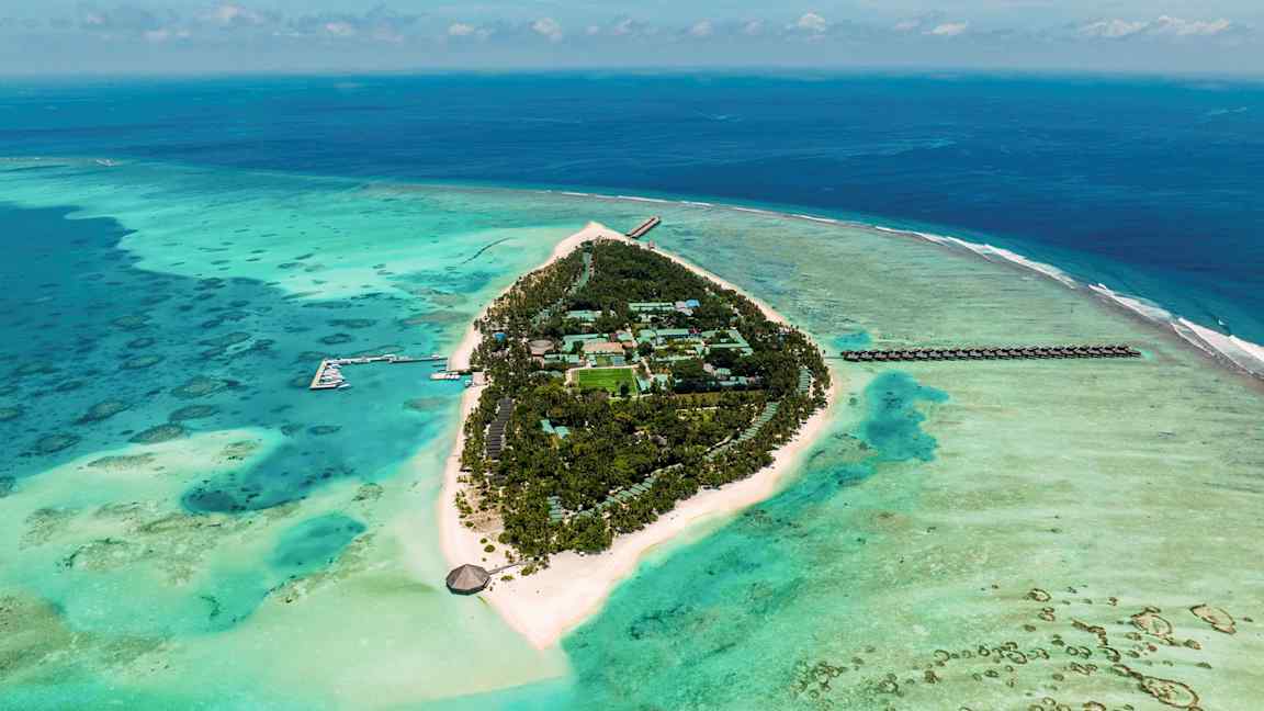 Flygvy av en tropisk ö omgiven av turkost hav med vita sandstränder och grön vegetation. (AI-genererad text)