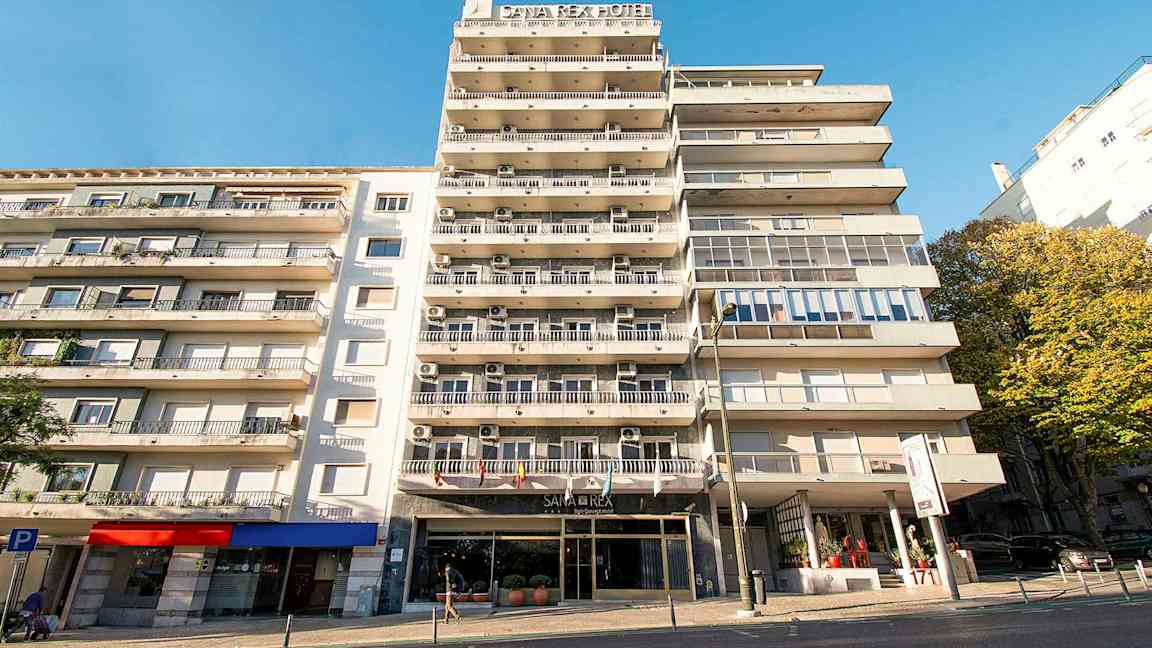 Flerbostadshus med hotellskylt och balkonger under en klarblå himmel. (AI-genererad text)