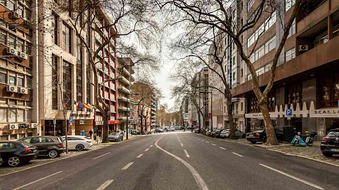 En bild av en tom stadsgata kantad av byggnader och träd. (AI-genererad text)