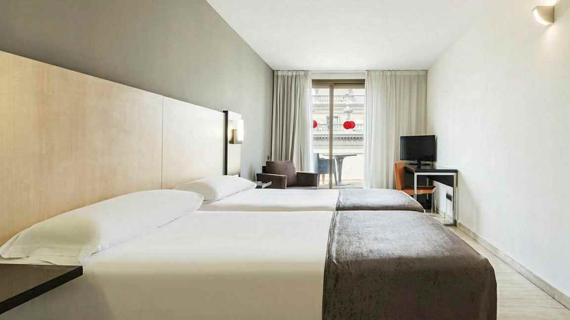 Hotellrum med två enkelsängar, skrivbord och balkong. (AI-genererad text)