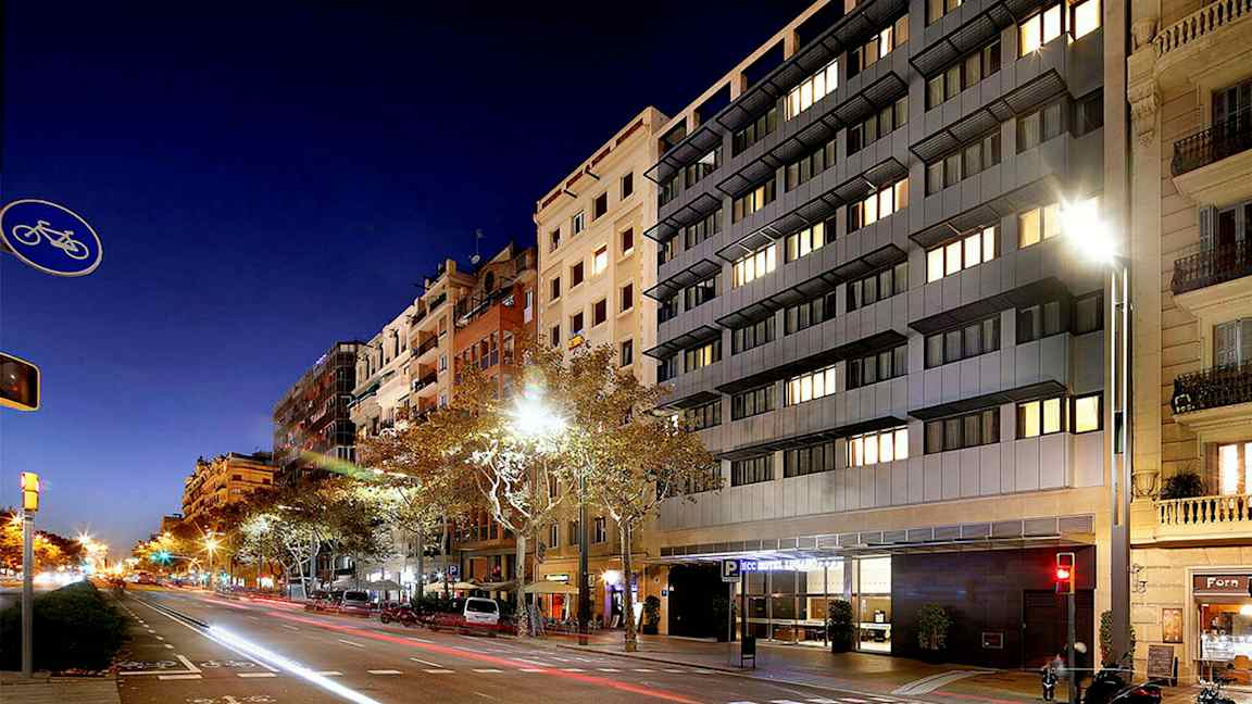 En gata i stadsmiljö på natten, med höga byggnader och bilar längs vägen. (AI-genererad text)