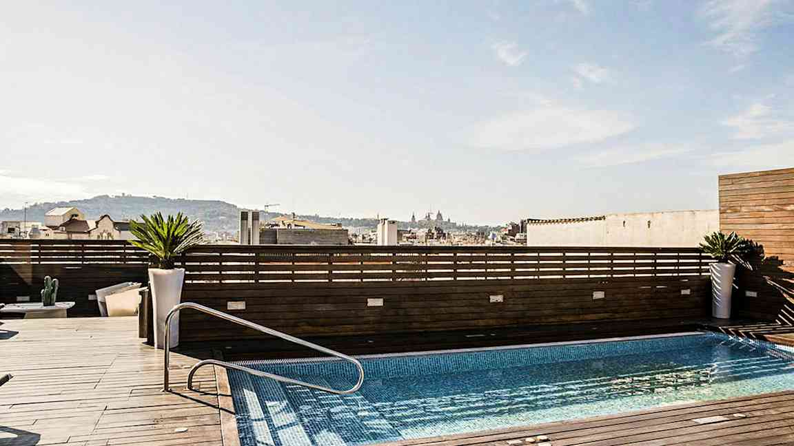En takterrass med en pool, omgiven av träpaneler och med utsikt över en stad. (AI-genererad text)