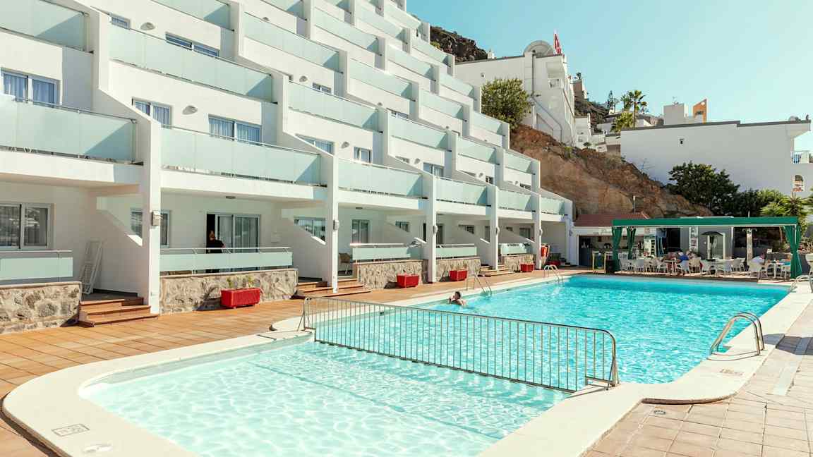Bild på hotellkomplex med pool och sittområde. (AI-genererad text)