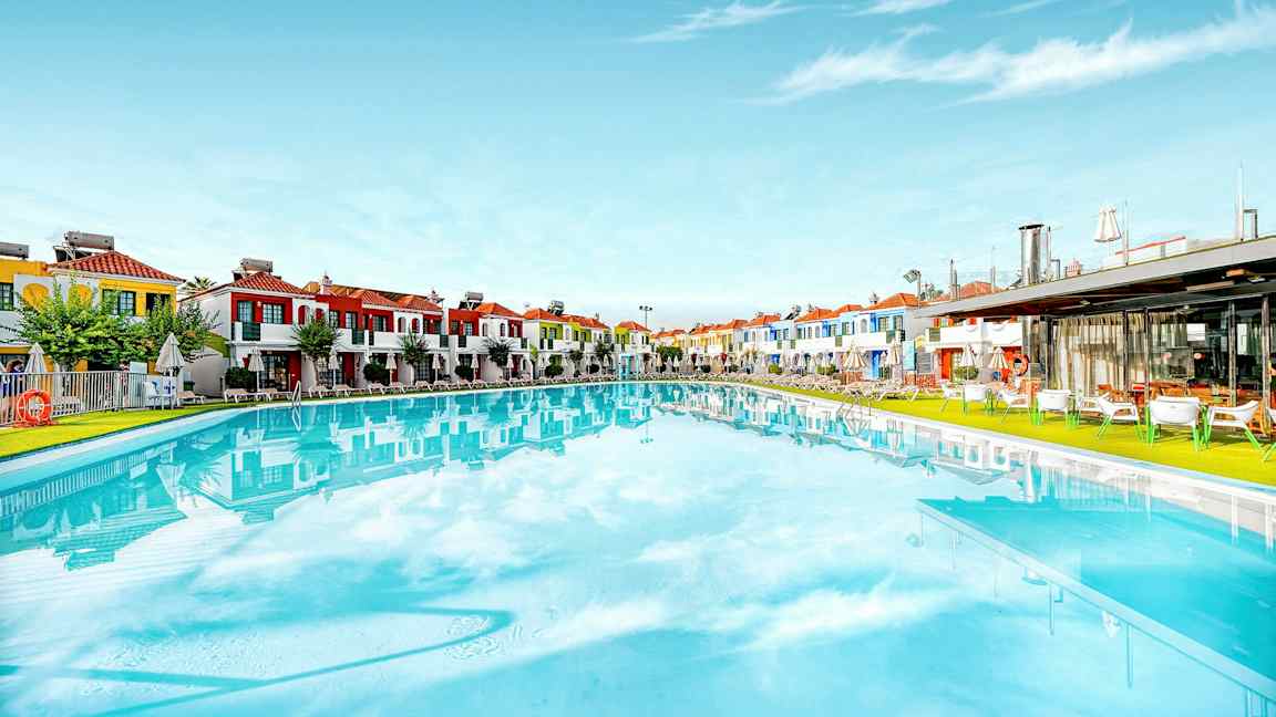 Stor pool med färgglada byggnader i bakgrunden. (AI-genererad text)