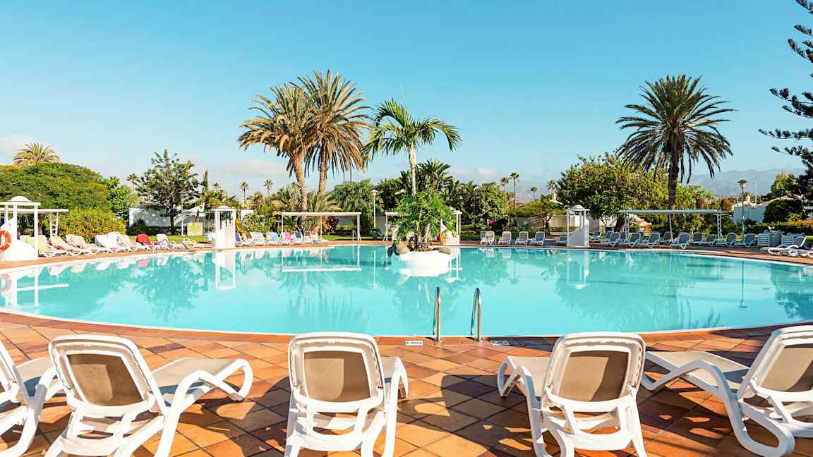 En stor pool omgiven av solstolar och palmer. (AI-genererad text)