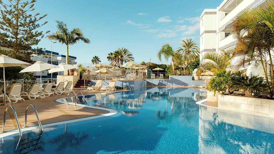 Utomhuspool med solstolar och parasoller vid ett hotell. (AI-genererad text)