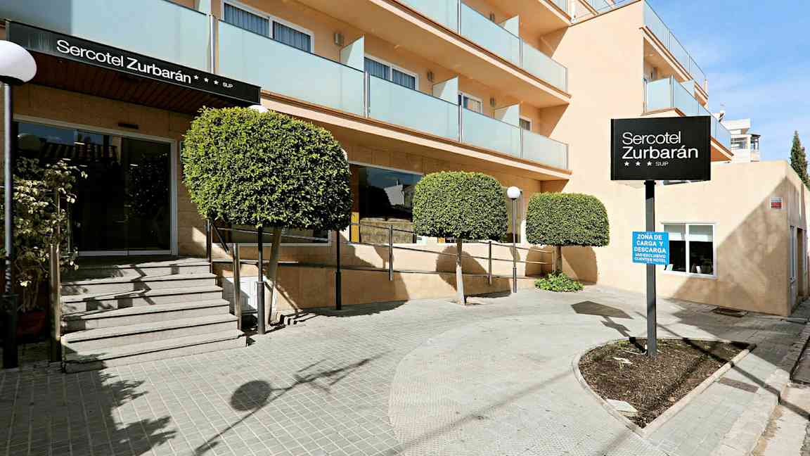 Bild av entrén till hotell Sercotel Zurbarán med träd och balkonger. (AI-genererad text)