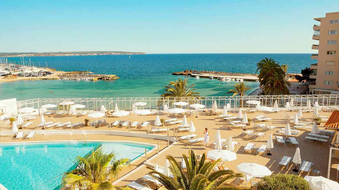 Poolområde med solstolar och parasoll nära havet. (AI-genererad text)