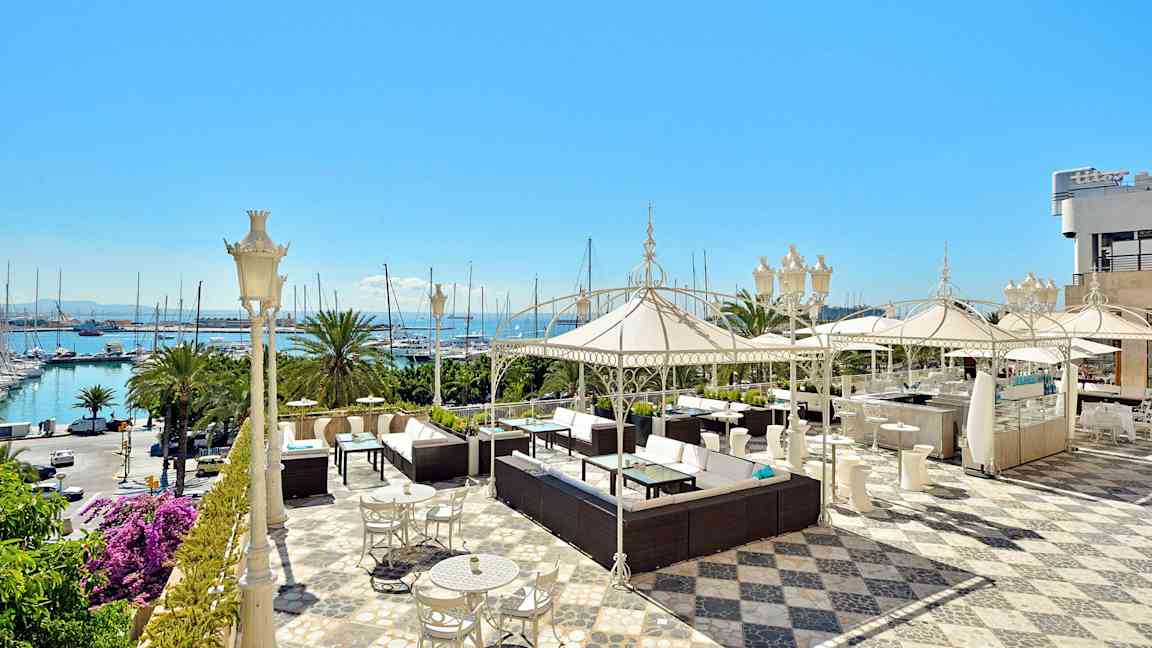 En rymlig terrass med sittgrupper, parasoller och havsutsikt. (AI-genererad text)