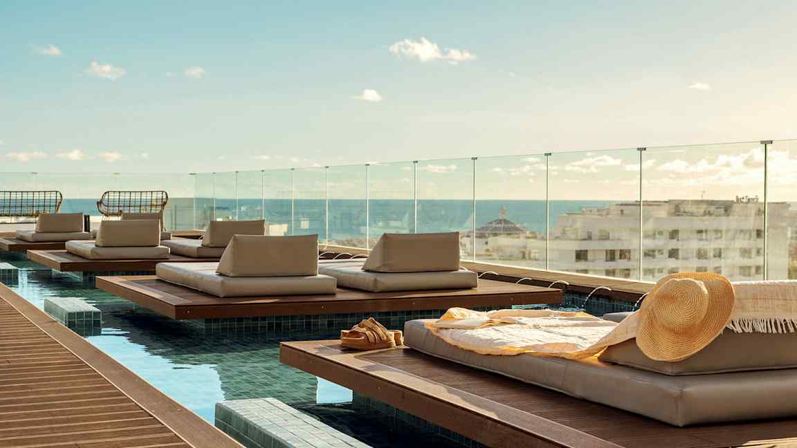 Liggplatser vid en pool med utsikt över staden och havet. (AI-genererad text)