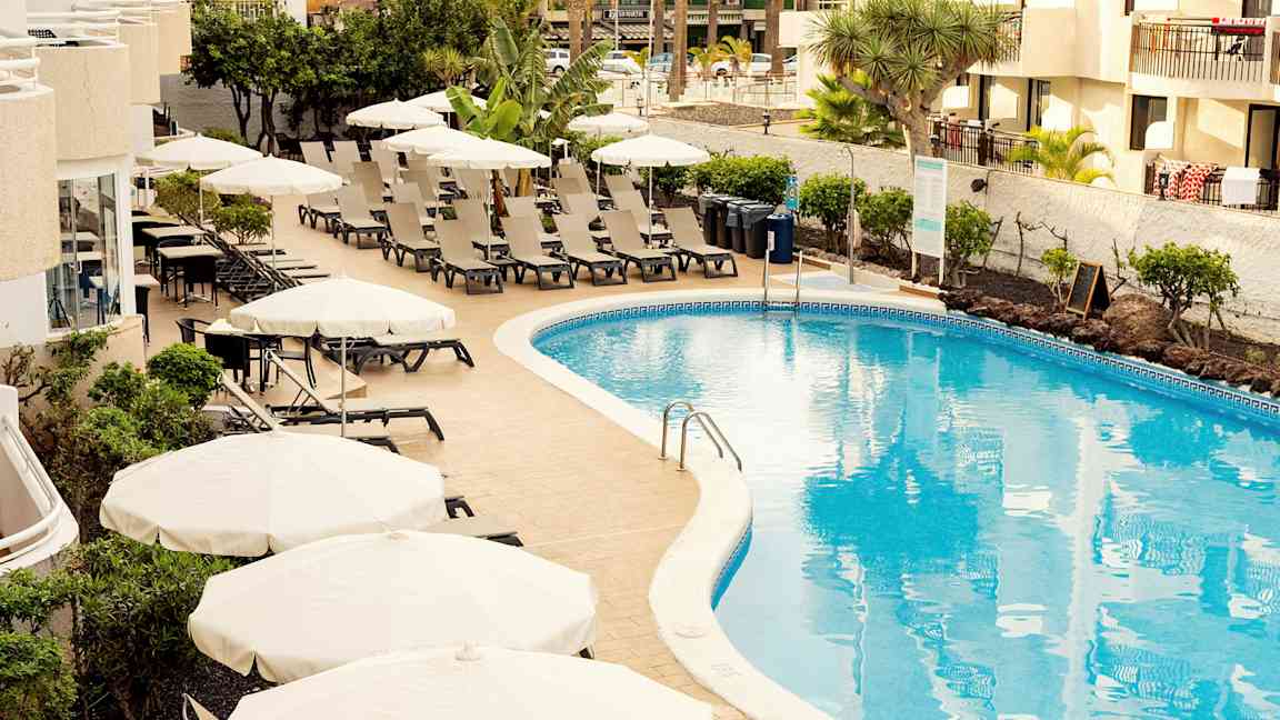 Poolområde med solstolar och parasoller vid ett hotell. (AI-genererad text)