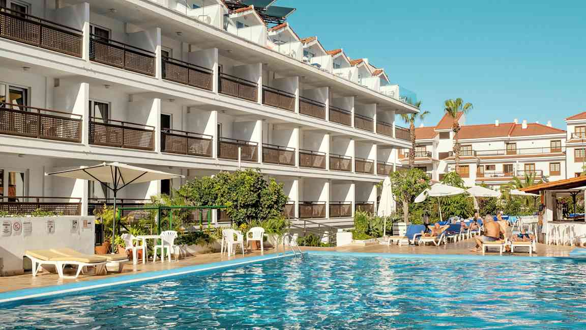Hotellbyggnad vid en swimmingpool. (AI-genererad text)