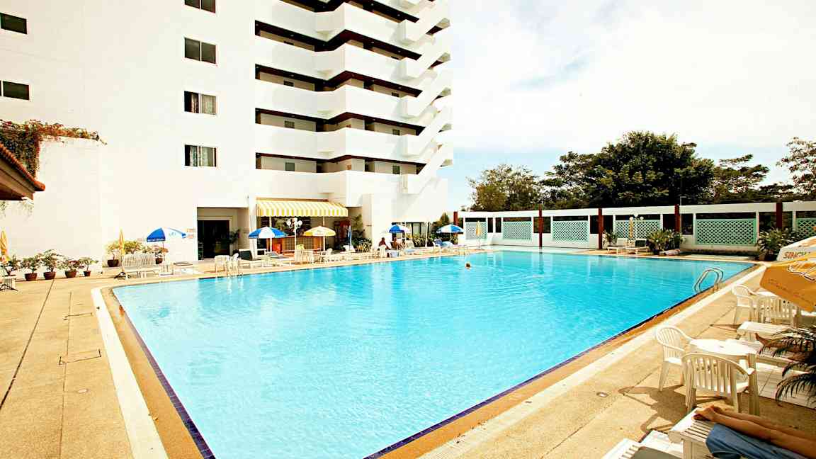 Utomhuspool vid ett hotell med solstolar och parasoller. (AI-genererad text)