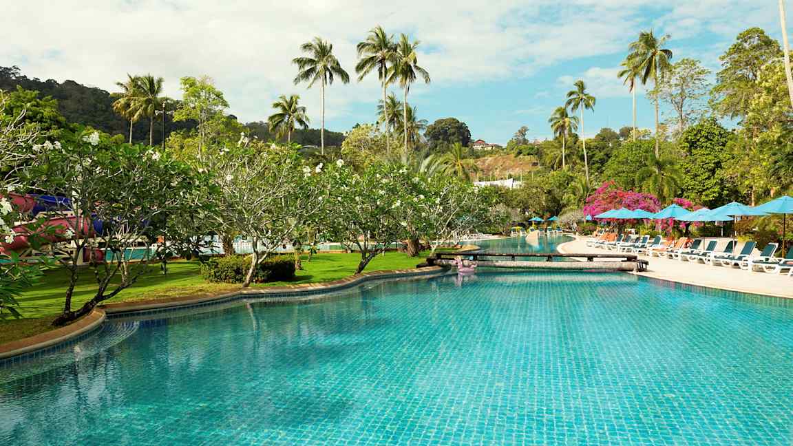 En swimmingpool omgiven av solstolar, parasoller och palmträd. (AI-genererad text)