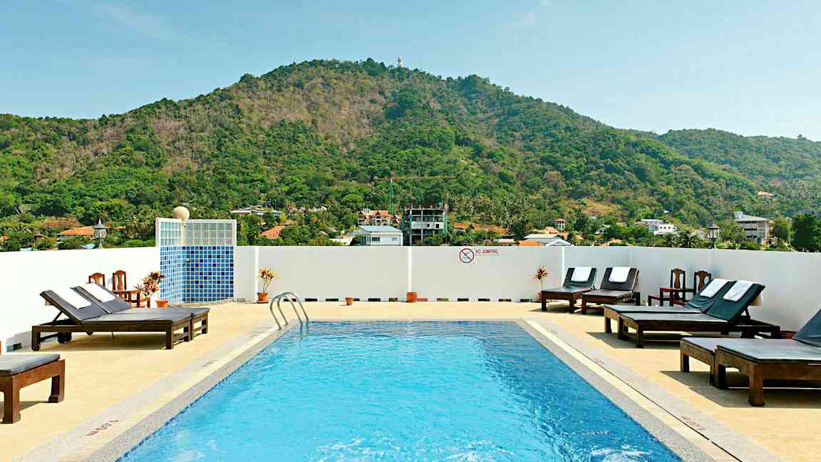 Utomhuspool med solstolar och berg i bakgrunden. (AI-genererad text)