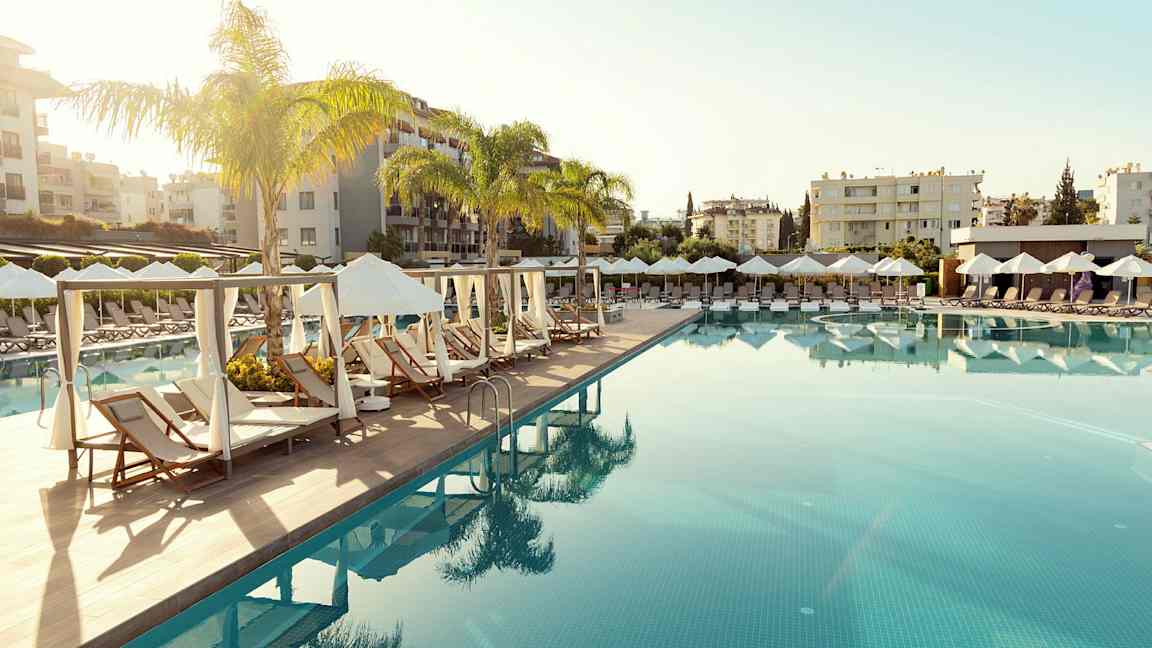 En pool med solstolar och parasoller i en resortmiljö. (AI-genererad text)