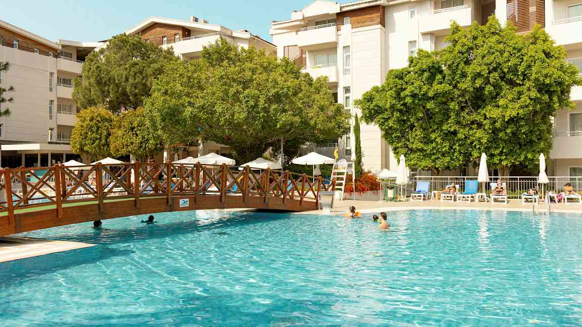 Utomhuspool med solstolar och träd i bakgrunden. (AI-genererad text)